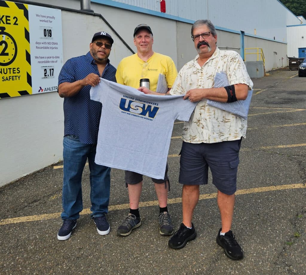 Three workers from Ahlstrom Windsor Locks hold a USW t-shirt.