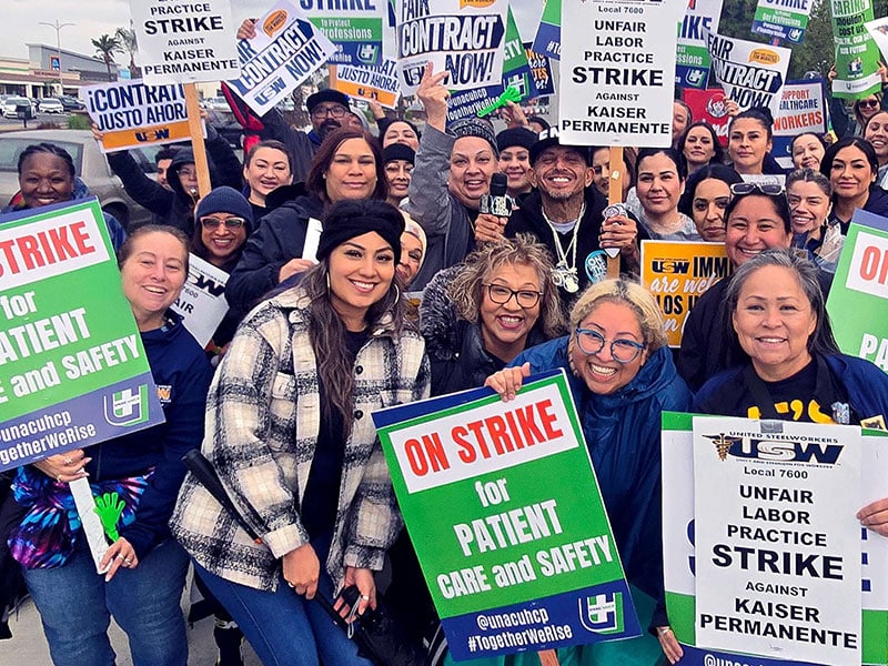Striking Inland Empire Kaiser Permanente workers hold signs saying "On Strike for Patient Care and Safety" and "Unfair Labor Practice Strike"