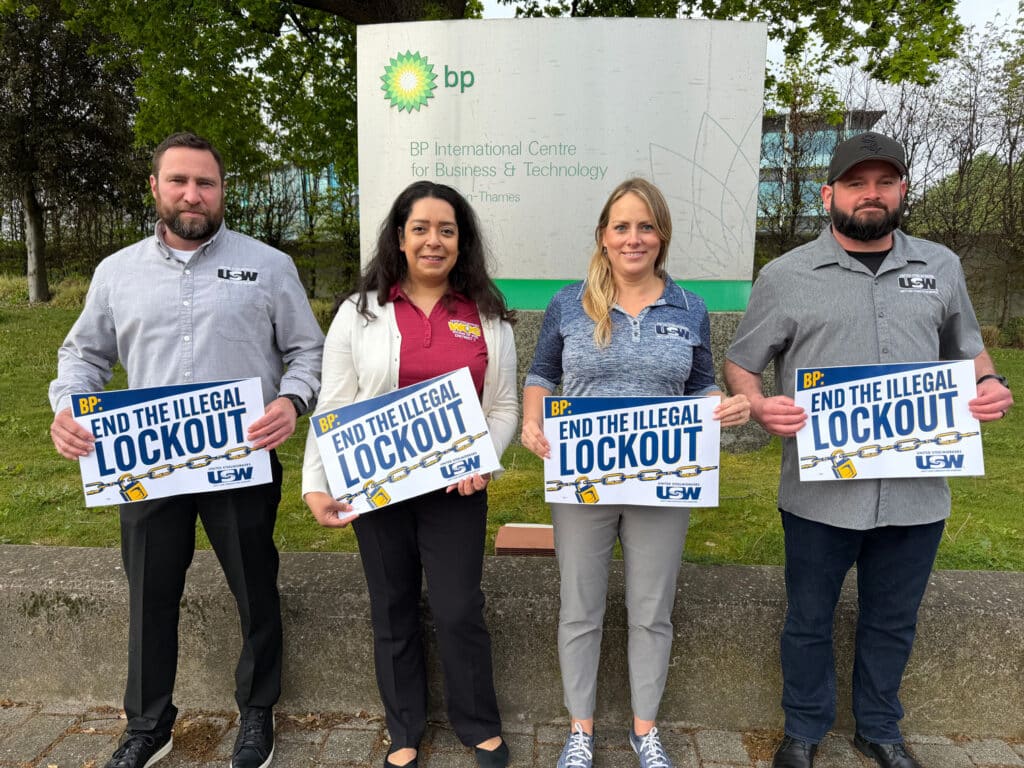 Four locked out members of USW Local 7-1 standing outside BP's London office holding signs that say 'End the Illegal Lockout.'